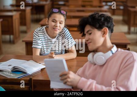 Cleveres Mädchen im Teenager-Alter, das während der Diskussion auf Notizen in Notizblock des Klassenkameraden hinweist Stockfoto