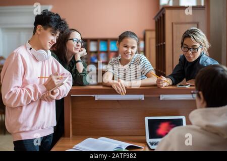 Gruppe cleverer Studenten, die vom Programmierer vor dem Laptop stehen Stockfoto