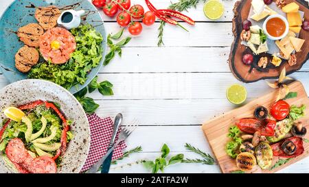 Ein Set Lebensmittel. Tatar, Käse, Salat und Gemüse. Auf Holzgrund. Draufsicht. Kopierbereich. Stockfoto