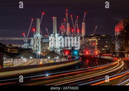 London. Ein stimmungsvolles Nachtfoto des Battersea Power Station, das leichte Wege von den Zügen zeigt. Stockfoto