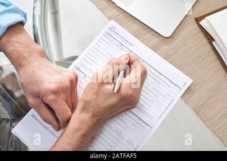 Hände des modernen, älteren Rentner, der das Formular für die Krankenversicherung ausgefüllt hat Stockfoto