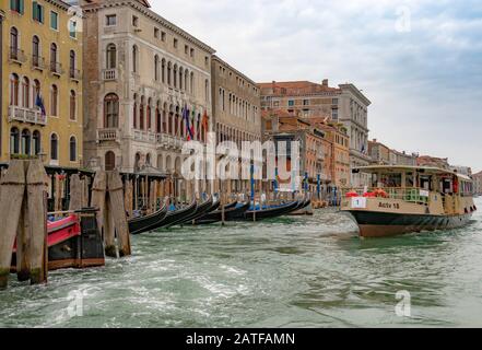 Eine Route 1 Vaporetto führt auf dem Canal Grande Von Venedig vorbei an einer Linie von Gondeln, einer Linie von Gondeln, Venedig, Italien Stockfoto