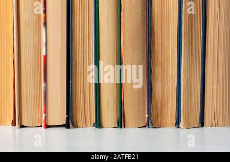 Alte und gut gebrauchte Hardback-Bücher oder Textbücher in einem Buchladen oder einer Bibliothek. Viele Bücher Stapeln Sich. Hardback-Bücher. Zurück zum Schulhintergrund mit Kopierbereich Stockfoto