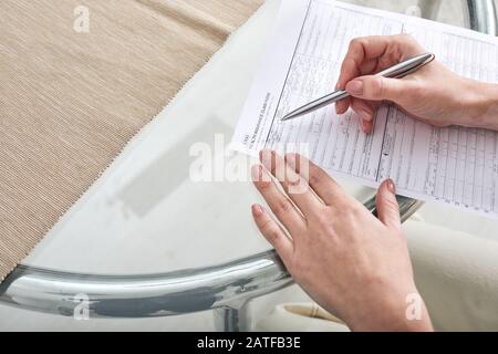 Hände junger Frauen mit Stift über Papier, die das Krankenversicherungsformular ausfüllen Stockfoto