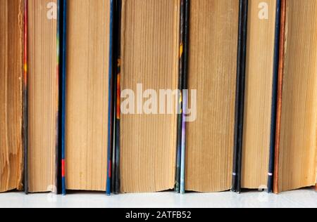 Alte und gut gebrauchte Hardback-Bücher oder Textbücher in einem Buchladen oder einer Bibliothek. Viele Bücher Stapeln Sich. Hardback-Bücher. Zurück zum Schulhintergrund mit Kopierbereich Stockfoto