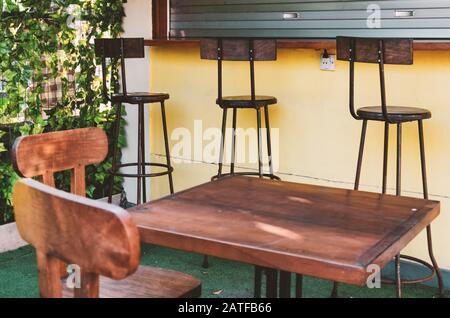 Blick auf den Innenhof eines Cafés im Freien an einem sonnigen Tag. Holzmöbel - Barhocker und Tische. Bali, Indonesien Stockfoto