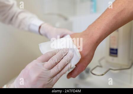 Die Pflegekraft desinfiziert die Hand eines Patienten an einem Waschbecken Stockfoto