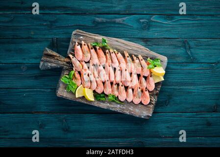 Garnelen auf einem Holzbrett. Meeresfrüchte. Auf dem alten Hintergrund. Draufsicht. Freier Speicherplatz. Stockfoto