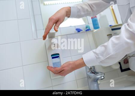 Eine Krankenschwester desinfiziert ihre Hände in einem Krankenhauszimmer Stockfoto