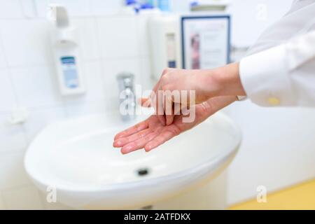 Eine Krankenschwester desinfiziert ihre Hände in einem Krankenhauszimmer Stockfoto