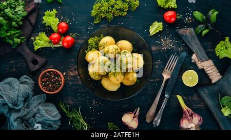 Gekochte Kartoffeln mit Dill in einer Schüssel. Auf Holzgrund. Draufsicht. Kopierbereich. Stockfoto