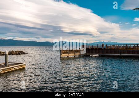 Touristen genießen den Sonnenuntergang mit ihrem Smartphone von einem Dock in Tahoe Vista Stockfoto