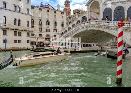 Wassertaxi, Vaporetto und andere kleine Boote machen sich unter Der Rialtobrücke auf den Weg, die älteste von vier Brücken, die den Canal Grande in Venedig überqueren Stockfoto