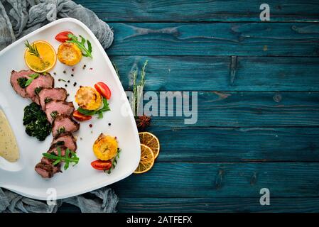 Kalbssteak mit Spinat und Mais. Auf Holzgrund. Draufsicht. Freier Speicherplatz Stockfoto