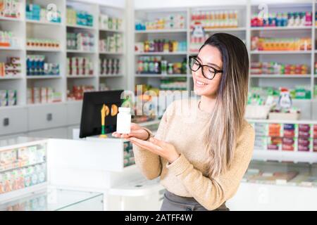 Schöne Frau Klientin in Apotheke mit weißem Glas und Arznei. Lächeln auf dem Gesicht Stockfoto