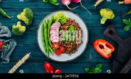 Linsen mit Rettich, Kirschtomaten, Bohnen und Gemüse. Gesunde Ernährung. Auf einem blauen Holztisch. Draufsicht. Freier Speicherplatz für Text. Stockfoto