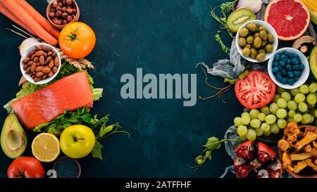 Ein Set gesunder Speisen auf einem Steintisch. Fisch, Gemüse, Obst, Nüsse, Beeren, Pilze. Draufsicht. Freier Speicherplatz für Text. Stockfoto