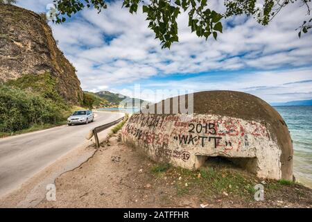 Unter dem kommunistischen Diktator Hoxha errichteter, mit Graffiti bedeckter Bunker am Ohridsee, mazedonisches Ufer in der Ferne, in der Nähe von Pogradec, Albanien Stockfoto