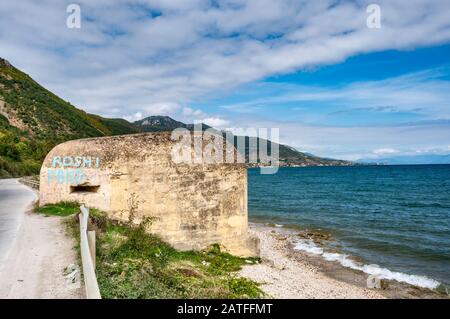 Unter dem kommunistischen Diktator Hoxha errichteter, mit Graffiti bedeckter Bunker am Ohridsee, mazedonisches Ufer in der Ferne, in der Nähe von Pogradec, Albanien Stockfoto