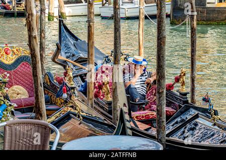 Ein Gondolier, der sich ausruhen kann, sitzt in seiner Gondel am Canal Grande, Venedig, Italien Stockfoto