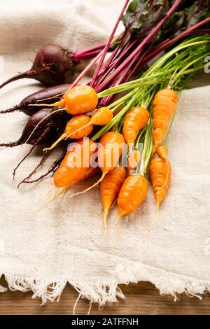 Bunte frische Karotten und rote Bete auf rustikalem Tuch Stockfoto