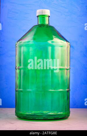 Ein 22-Liter-Glasbecher besteht aus dickem grünem Glas, Bild auf blauem Hintergrund. Stockfoto