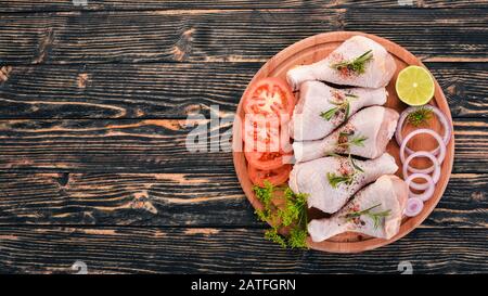 Rohe Hühnerbeine mit Gewürzen und Gemüse. Auf Holzgrund. Draufsicht. Kopierbereich. Stockfoto