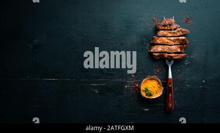 Schweinesteak auf der Gabel. Auf Holzgrund. Draufsicht. Freier Speicherplatz für Ihren Text. Stockfoto