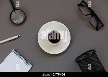 Arbeitsplatz-Wohnung lag von oben. Geöffneter Notizblock, Brille, eine Lupe auf Pastell-Backgrun. Stockfoto