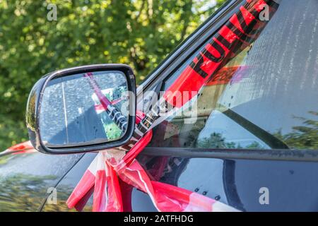 Seitenspiegel eines Autos nach einem heftigen Unfall mit Polizeisperrband in rot-weiß mit dem deutschen Wort für Polizeibarrikade, Deutschland Stockfoto