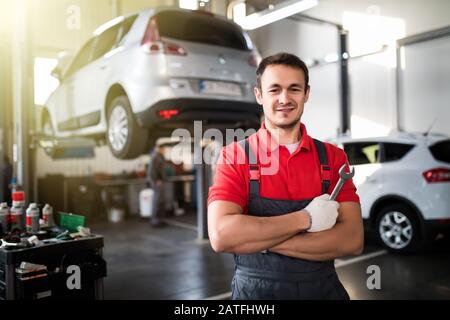 Porträt des jungen Mechanikers mit gekreuzten Armen in seiner Werkstatt Stockfoto