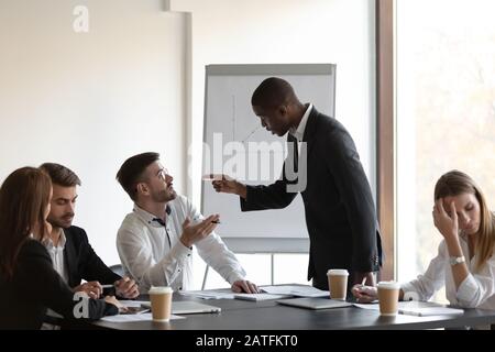 Multiethnische Geschäftsleute, die sich bei Treffen gegenseitig beschuldigen Stockfoto