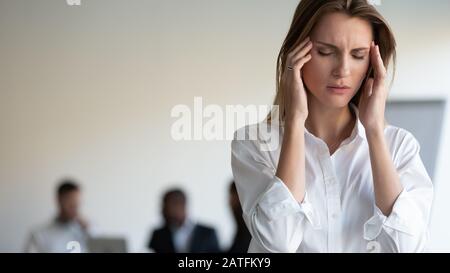 Frau berührt Tempel leidet unter Kopfschmerzen durch Stress am Arbeitsplatz Stockfoto