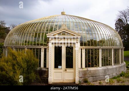 Glashaus im Sommer. Altes Vintage-Glashaus aus den siebziger Jahren noch in Gebrauch. Garten mit Gartenmöbeln Stockfoto
