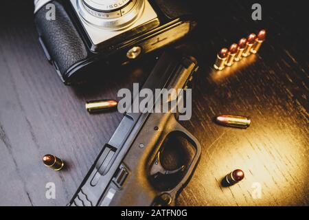 Pistole, Kamera und Kugeln auf Holztisch Stockfoto
