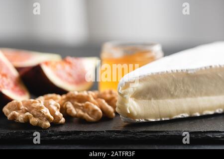 Brie- oder Camembert-Käse, Walnüsse, Honig, Feigen. Käseplatte. Nahansicht Stockfoto