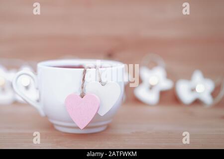 Herzförmige Teetasche in weißer Tasse Tee - süße Liebeserklärung auf Holzhintergrund, selektiver Fokus. Valentines Tageskonzept. Tasse Tee für zwei Liebhaber Flitterwochen Hochzeit Morgen Überraschung Frühstück Stockfoto