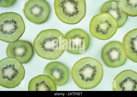 Muster der Kiwischeiben, die über hellgrünem Hintergrund schweben Stockfoto