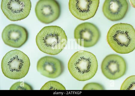 Muster der Kiwischeiben, die über hellgrünem Hintergrund schweben Stockfoto