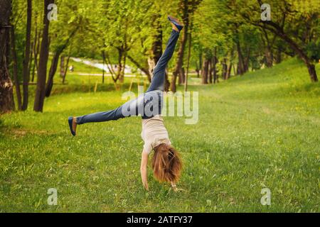 Mädchen macht ein akrobatisches Rad. Auf dem Gras. Stockfoto