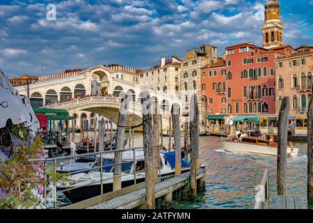 Ein Wassertaxi auf Dem Canal Grande führt vorbei an einem Anlegesteg mit Holzständern zur Rialto-Brücke, Venedig, Italien Stockfoto