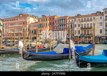 Nahaufnahme der Metallklinge oder Fero da prora, an der Vorderseite einer leeren Venetian Gondola, die an einen Holz-Anlegepfosten am Canal Grande, Venedig, gebunden ist Stockfoto