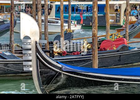 Nahaufnahme der Metallklinge oder Fero da prora, an der Vorderseite einer leeren Venetian Gondola, die an einen Holz-Anlegepfosten am Canal Grande, Venedig, gebunden ist Stockfoto