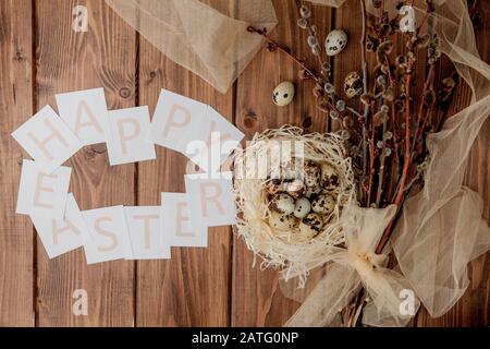 Flache Laienzusammensetzung aus Wachteleiern und Karte mit Text Happy Easter auf Holztisch. Draufsicht. Stockfoto