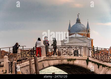 Die Leute, die eine Brücke mit der Kirche des Santissimo Redentore auf Guidecca Isalnd im Hintergrund, Venedig, Italien, stehen Stockfoto