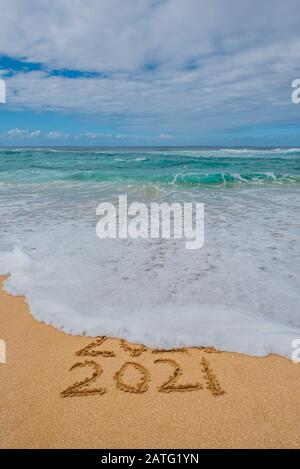 2020 2021 im Sand geschrieben mit einer Welle, die 2020 wegspült - Neujahrskonzept Stockfoto