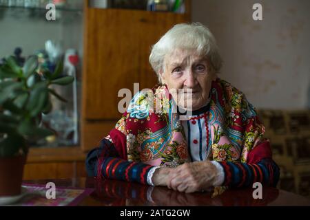 Eine alte Frau in ukrainischer Kleidung, die zu Hause sitzt. Stockfoto