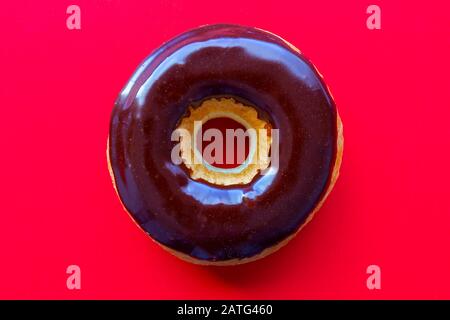 Ein Schokoladendip Donut auf rotem Hintergrund Stockfoto
