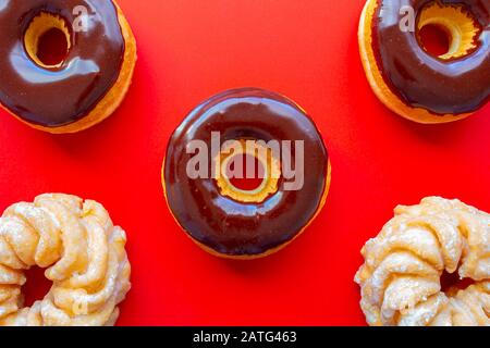 Schokoladendip Donuts mit Honey Cruller Donuts auf rotem Hintergrund Stockfoto