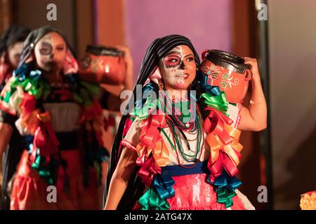 Indianapolis, Indiana, USA - 2. November 2019: Day of the Dead, junge mexikanische Frauen mit Gesichtsfarbe am Schädel, die traditionelle Kleidung tragen und TR durchführen Stockfoto
